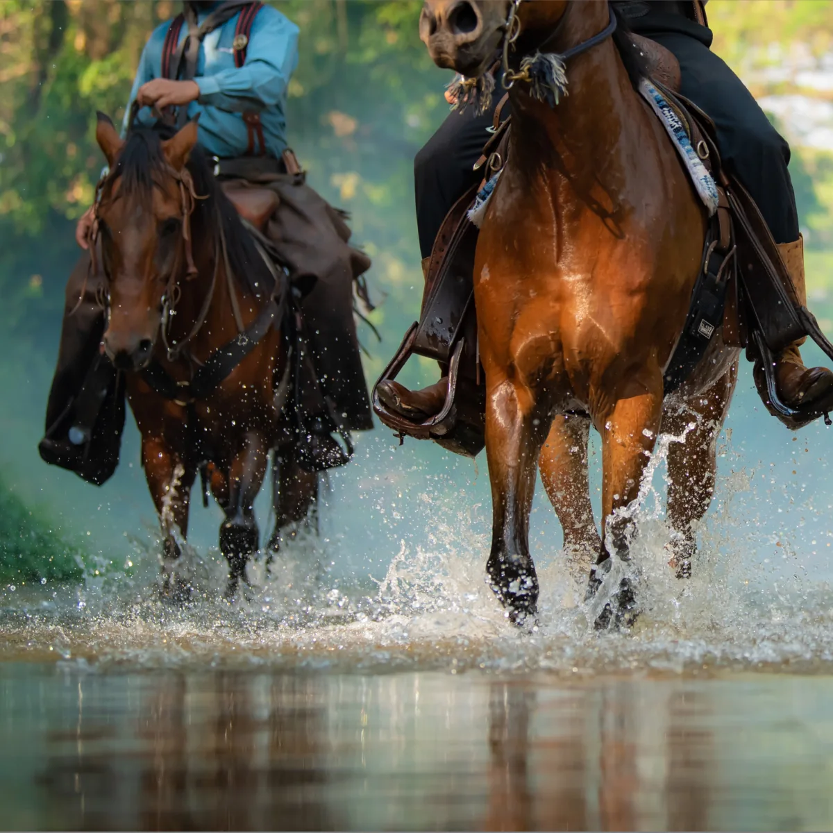 Two people riding on horses through a river.